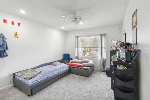 bedroom with ceiling fan, light colored carpet, and a textured ceiling