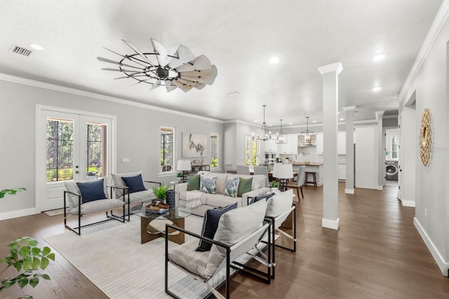 living room with dark wood-type flooring, ornamental molding, washer / dryer, and ornate columns