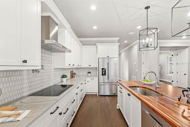 kitchen with high quality fridge, white cabinetry, sink, wooden counters, and wall chimney range hood