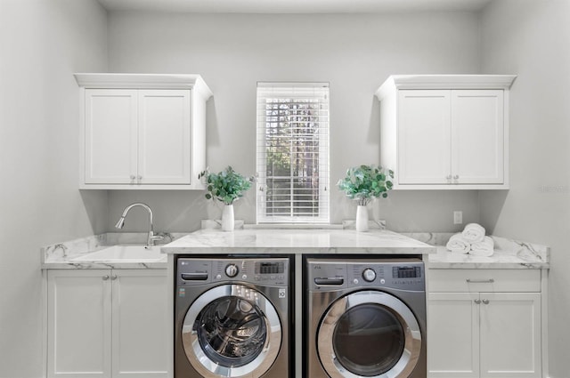 clothes washing area with cabinets, sink, and washer and clothes dryer