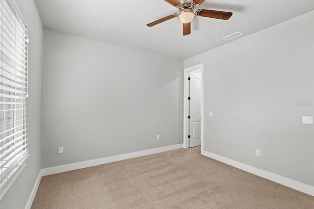 empty room featuring ceiling fan, a healthy amount of sunlight, and light carpet