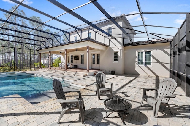 view of pool with french doors, a patio, ceiling fan, and glass enclosure