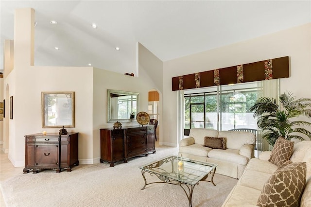 living room with high vaulted ceiling and light carpet