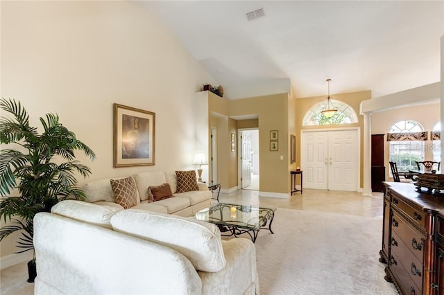 carpeted living room featuring high vaulted ceiling and ornate columns