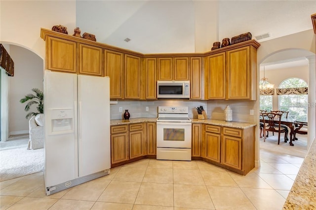 kitchen featuring high vaulted ceiling, backsplash, light tile patterned floors, light stone countertops, and white appliances