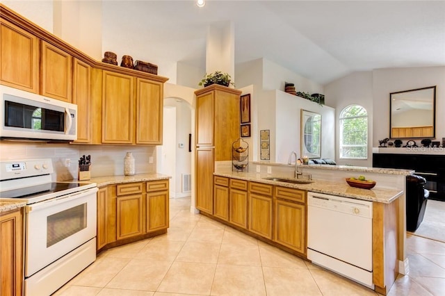 kitchen with vaulted ceiling, sink, kitchen peninsula, light stone countertops, and white appliances