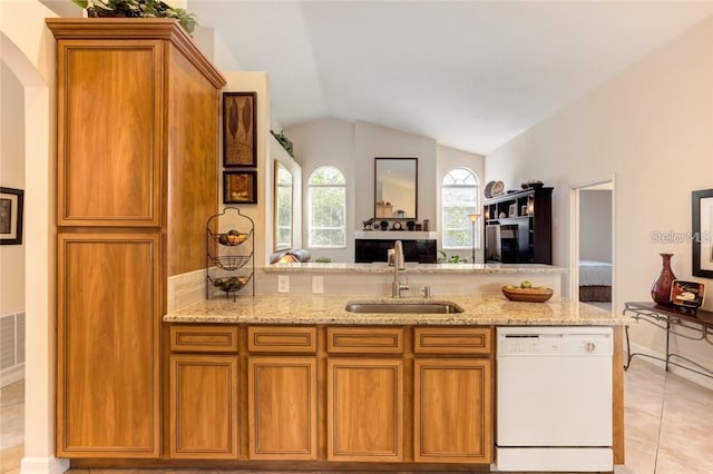 kitchen with sink, light tile patterned floors, dishwasher, light stone counters, and vaulted ceiling