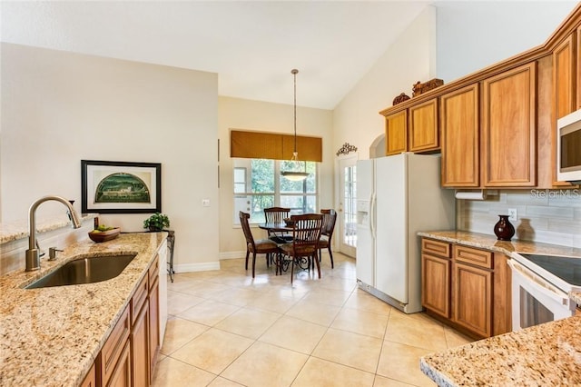 kitchen with pendant lighting, sink, decorative backsplash, light stone countertops, and white appliances