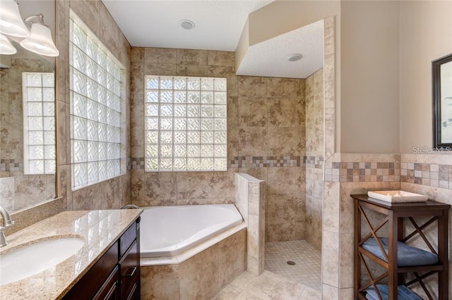 bathroom with tile patterned flooring, vanity, shower with separate bathtub, and tile walls