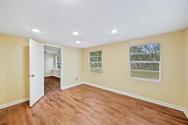 spare room featuring recessed lighting, baseboards, and wood finished floors