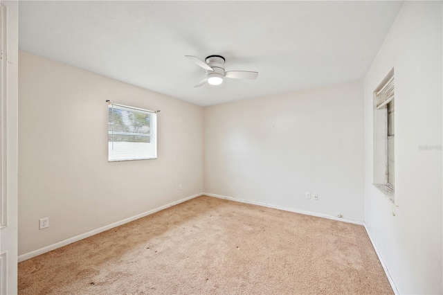 carpeted empty room featuring a ceiling fan and baseboards