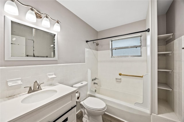 full bathroom with vanity, shower / bathing tub combination, wainscoting, tile walls, and toilet