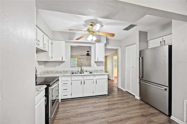 kitchen with wood finished floors, visible vents, a sink, white cabinets, and appliances with stainless steel finishes