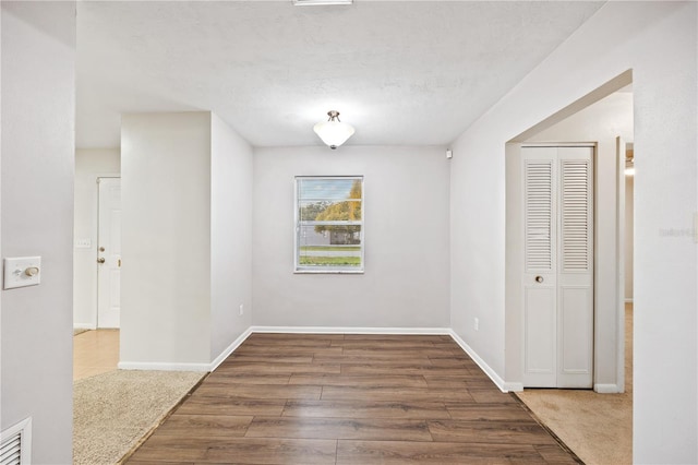 spare room with visible vents, baseboards, and wood finished floors