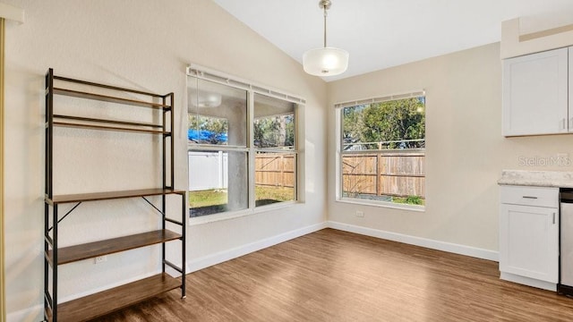 unfurnished dining area with wood-type flooring and lofted ceiling