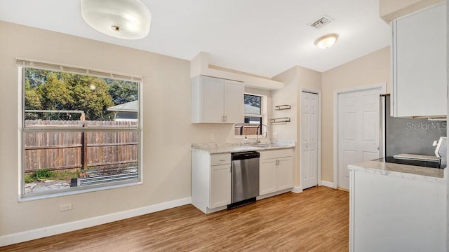 kitchen featuring stainless steel dishwasher, plenty of natural light, sink, and white cabinetry