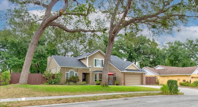 traditional-style house with concrete driveway, a front lawn, an attached garage, and fence