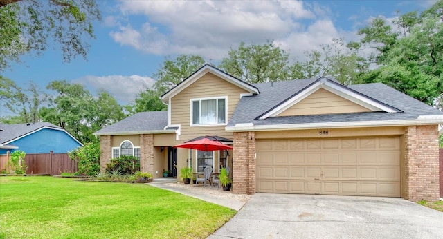 traditional-style home with an attached garage, brick siding, fence, concrete driveway, and a front lawn