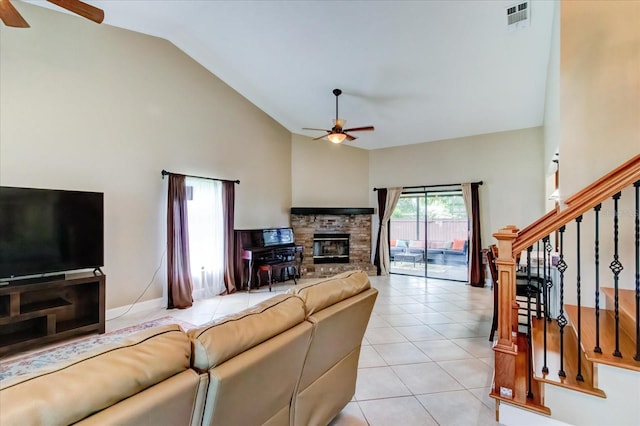 living area featuring light tile patterned floors, visible vents, stairway, a ceiling fan, and a glass covered fireplace
