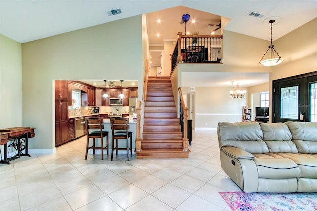 living area with stairway, visible vents, high vaulted ceiling, and light tile patterned flooring