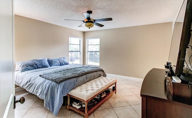 bedroom with light tile patterned floors, ceiling fan, baseboards, and a textured ceiling
