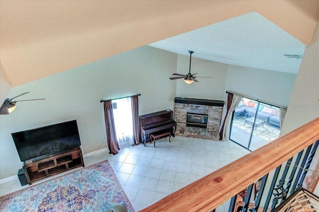 living area featuring ceiling fan, light tile patterned floors, a stone fireplace, high vaulted ceiling, and visible vents