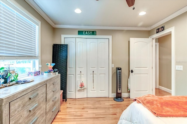 bedroom with a ceiling fan, baseboards, light wood-style floors, ornamental molding, and a closet