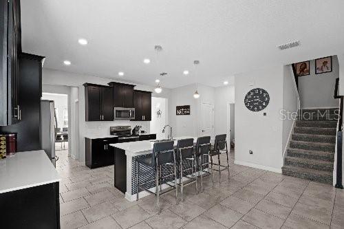 kitchen with pendant lighting, an island with sink, sink, a kitchen bar, and stainless steel appliances