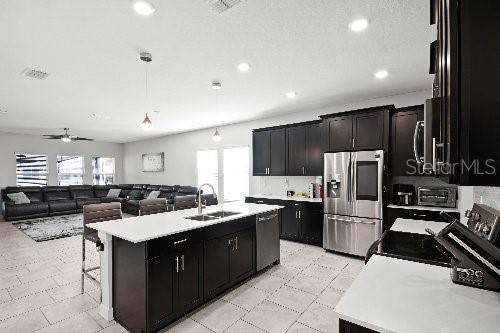 kitchen featuring stainless steel appliances, sink, an island with sink, and a wealth of natural light