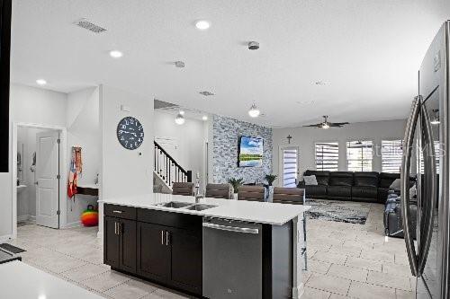 kitchen featuring ceiling fan, stainless steel appliances, sink, and a center island with sink