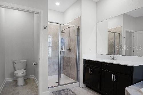 bathroom with tile patterned flooring, vanity, an enclosed shower, and toilet