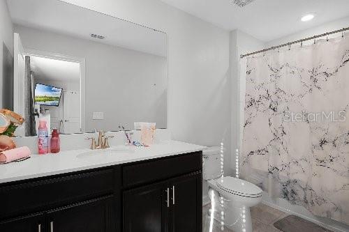 full bathroom featuring vanity, tile patterned floors, shower / bath combination with curtain, and toilet