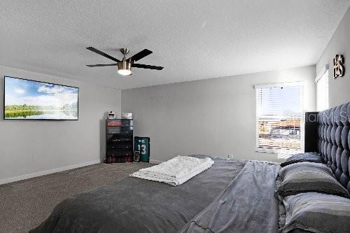 bedroom featuring ceiling fan, a textured ceiling, and carpet