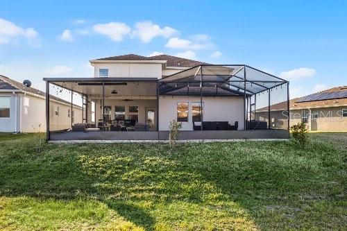 back of house with a lanai, a lawn, and a patio