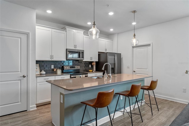 kitchen featuring pendant lighting, sink, stainless steel appliances, and a center island with sink