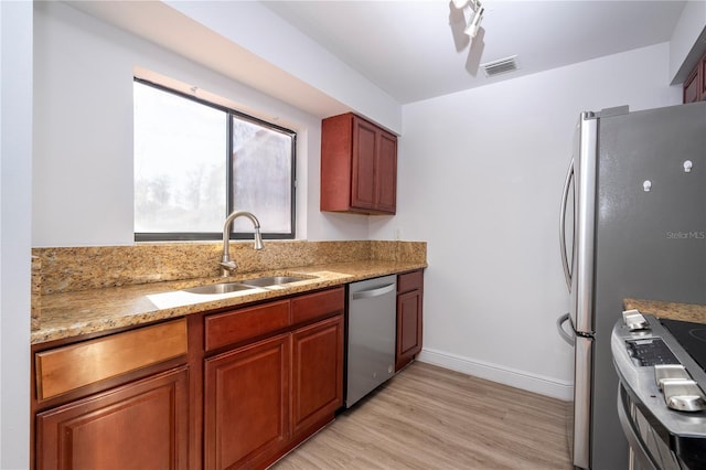 kitchen with light stone counters, sink, light hardwood / wood-style floors, and appliances with stainless steel finishes