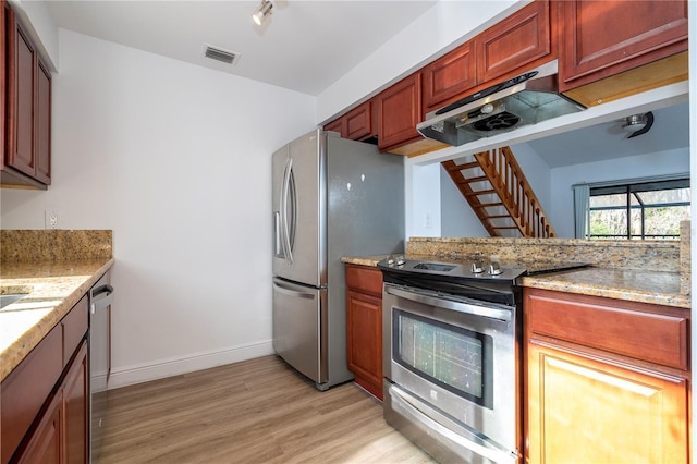 kitchen featuring appliances with stainless steel finishes, light stone counters, and light hardwood / wood-style flooring