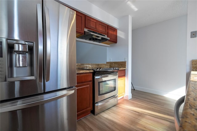 kitchen featuring appliances with stainless steel finishes, a textured ceiling, light hardwood / wood-style flooring, and stone counters