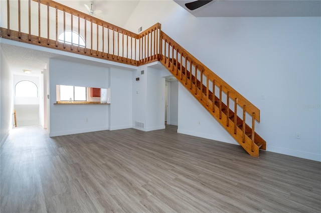 unfurnished living room with ceiling fan, high vaulted ceiling, and hardwood / wood-style floors