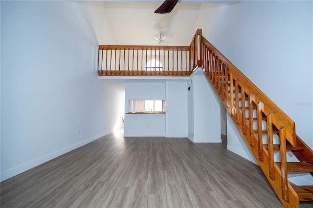 unfurnished living room with hardwood / wood-style flooring, a high ceiling, and ceiling fan