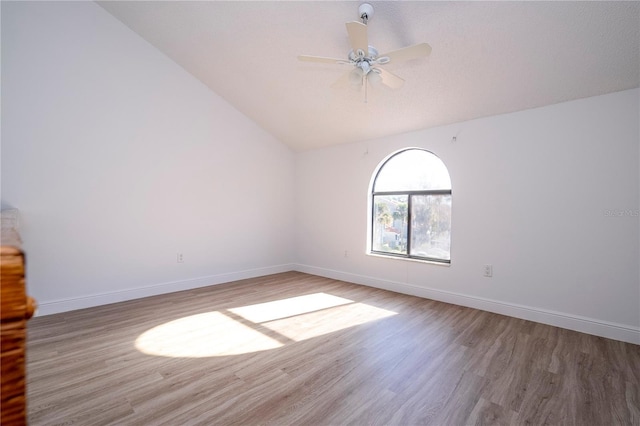 spare room with ceiling fan, wood-type flooring, and vaulted ceiling