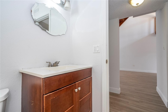 bathroom with hardwood / wood-style flooring, vanity, a textured ceiling, and toilet