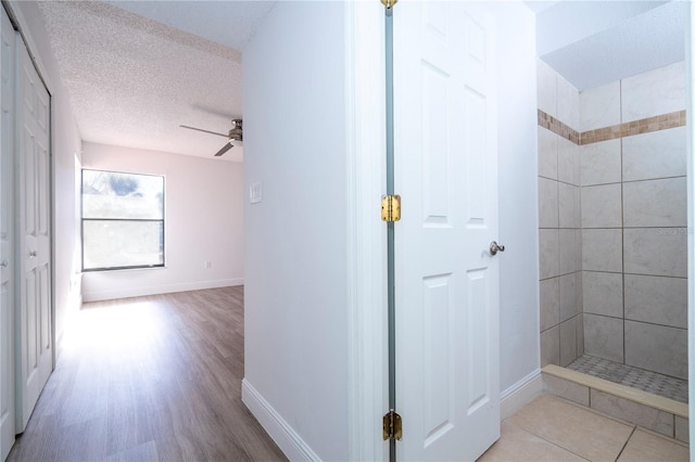 bathroom featuring a tile shower, ceiling fan, hardwood / wood-style flooring, and a textured ceiling