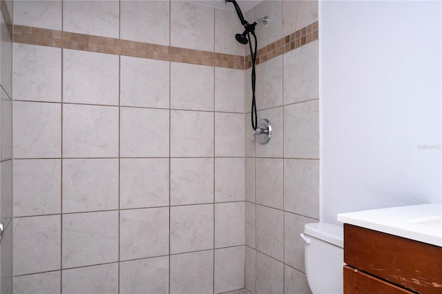 bathroom with vanity, toilet, and a tile shower