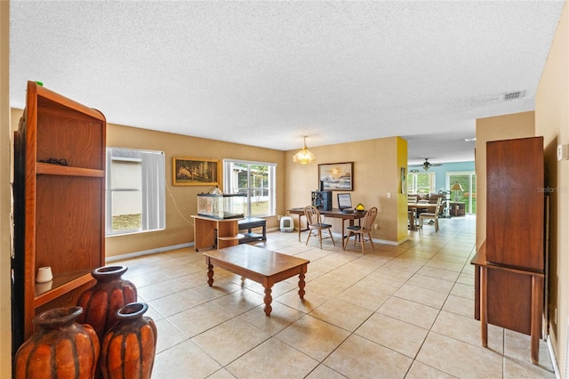 living room with ceiling fan, light tile patterned floors, and a textured ceiling