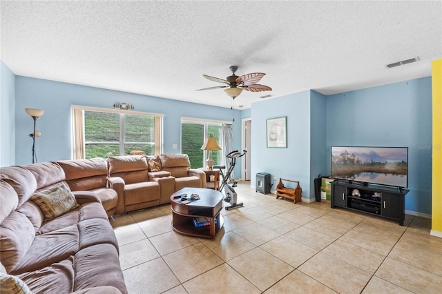 living room with a textured ceiling, ceiling fan, and light tile patterned flooring