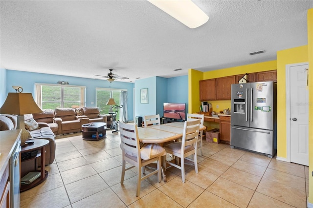 tiled dining room with a textured ceiling and ceiling fan