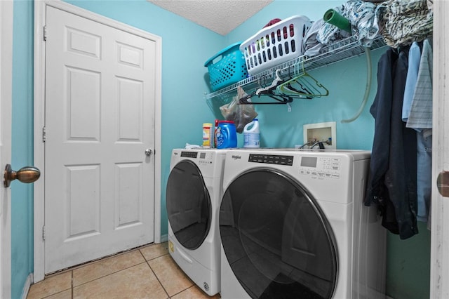 clothes washing area featuring separate washer and dryer, a textured ceiling, and light tile patterned floors