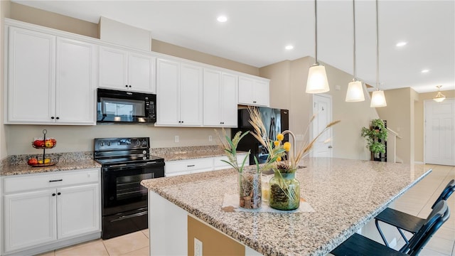 kitchen featuring pendant lighting, white cabinetry, a kitchen island with sink, light stone counters, and black appliances