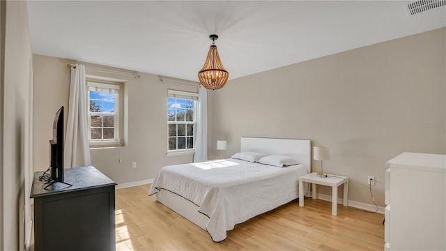 bedroom featuring light hardwood / wood-style flooring and a chandelier